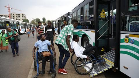 Image of people with disabilities in Rwanda getting on a bus.